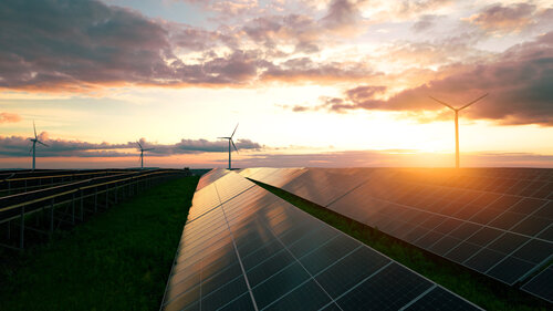 Green energy reduce carbon emissions and makes earth cleaner and more ecological. Solar panels park and wind turbines at sunset.Windmill turbines generating green energy electric