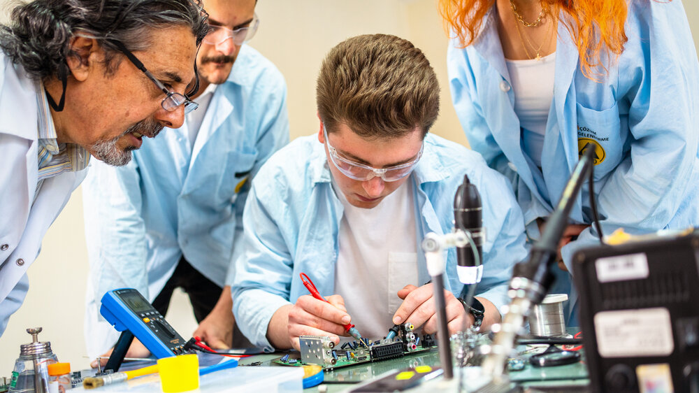 Gruppe junger Menschen in technischer Berufsausbildung mit Lehrer.