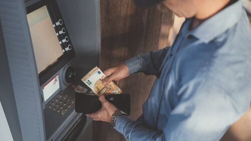 Businessman at the ATM withdrawing money, fifty euro banknotes