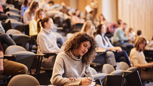 Studenten im Hörsaal einer Universität schreiben eine Klausur. 