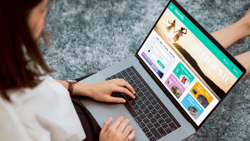 Frau sitzt in ihrem Haus mit Laptop und Buchung Flug Reise Suche Ticket Urlaub und Hotel auf Website.