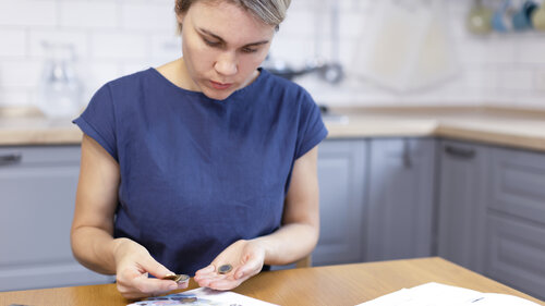 Eine blonde Frau hält Münzen in den Händen, zählt Geld.
