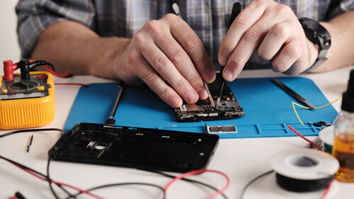 Servicetechniker prüft kaputtes Telefon vor der Reparatur.