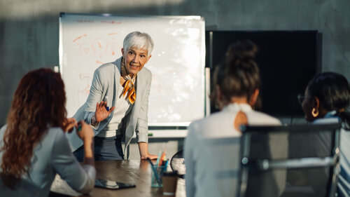 Führungskraft der Babyboomer-Generation mit Briefing im Büro mit ihrem Team. 