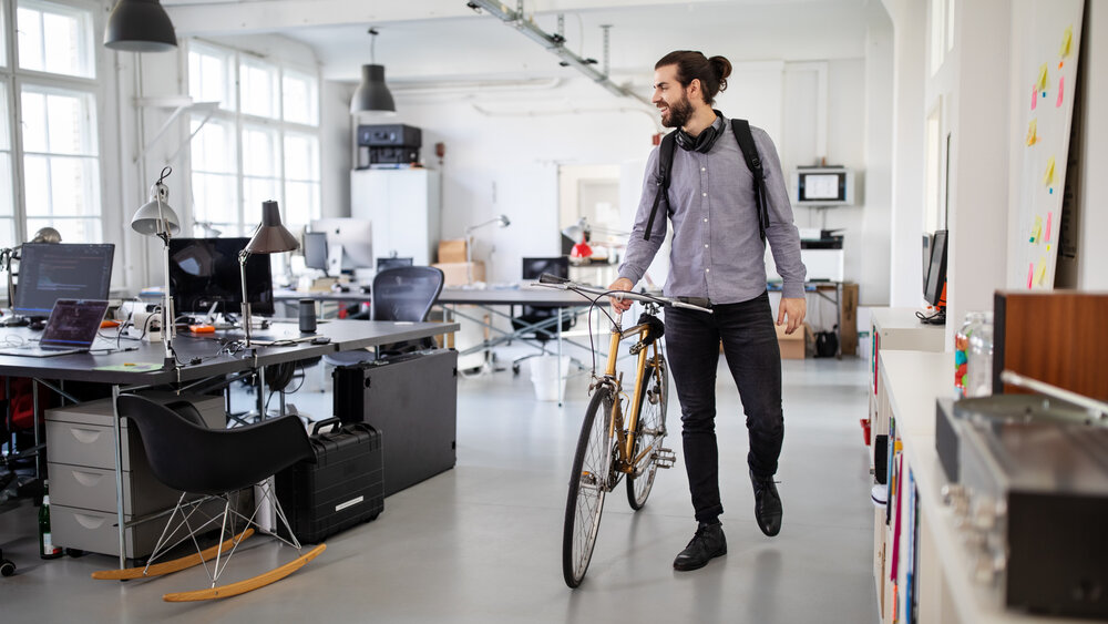 Businessman with a bicycle in office. Business professional going home after work.